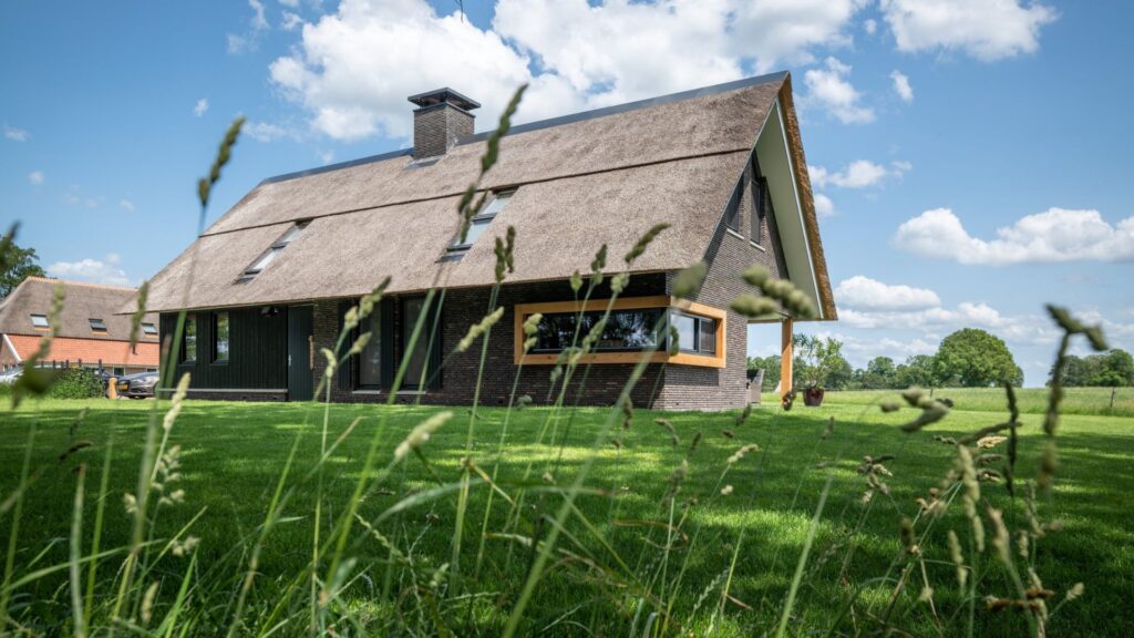 Foto vanaf het gras genomen met daarop een rietgedekte schuurwoning | Brick Finesse